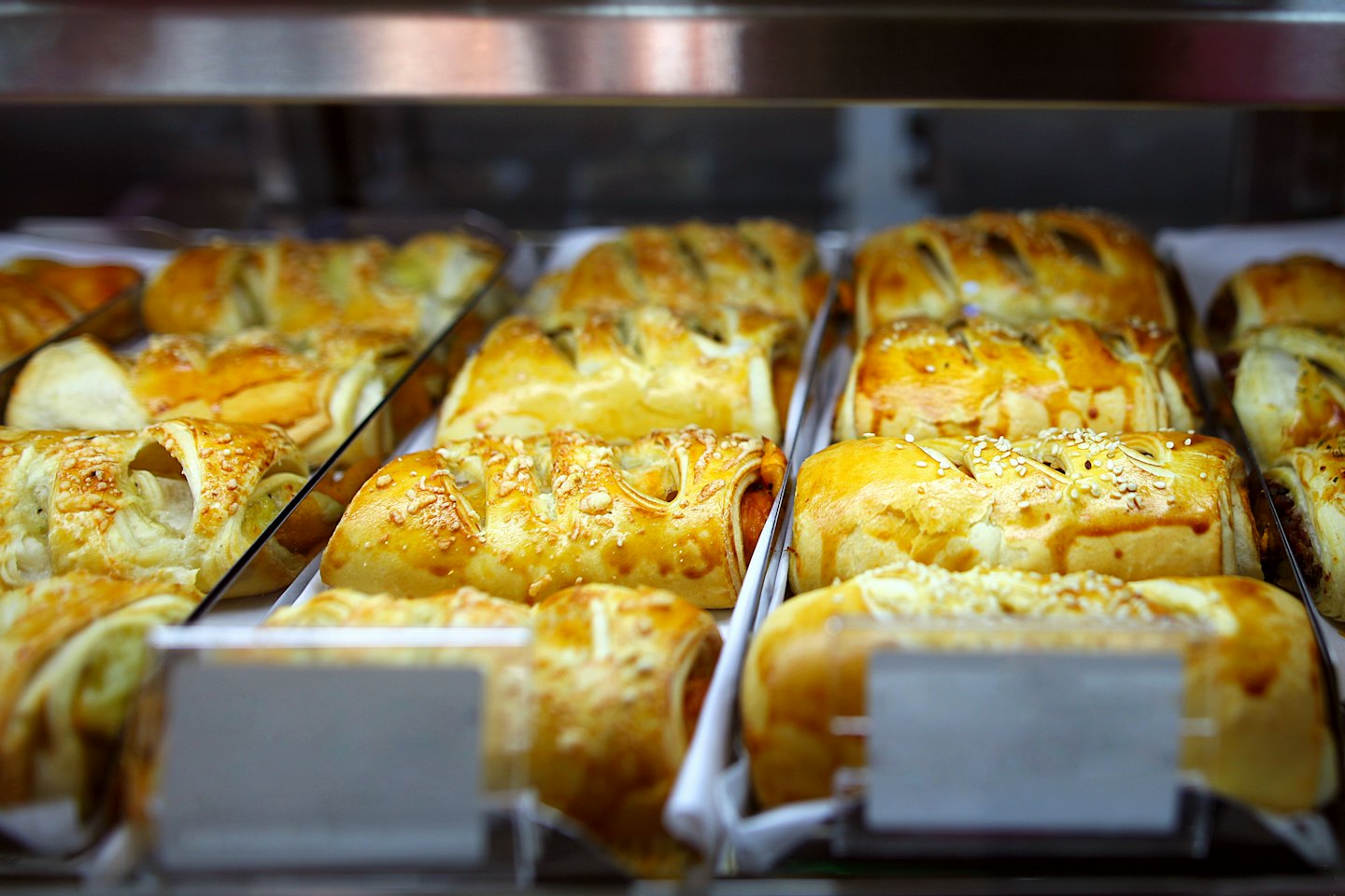 Rows of golden baked pastries arranged in a glass display.