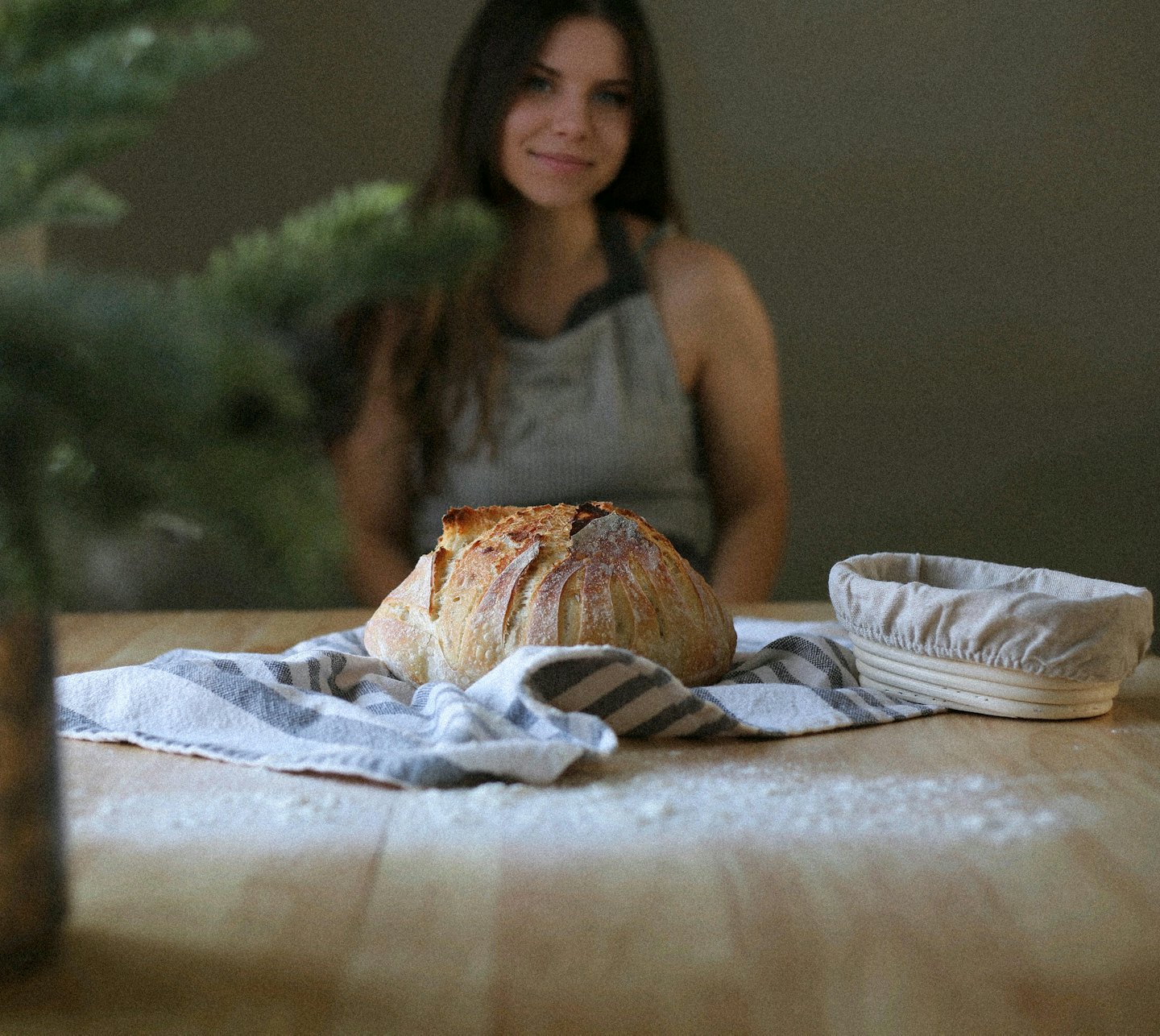 Sourdough bread rests on a linen towel next to a basket.